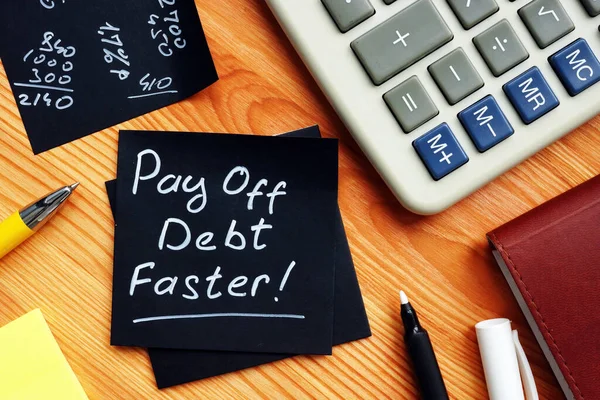 Rembourser la dette plus rapidement note manuscrite et calculatrice. — Photo