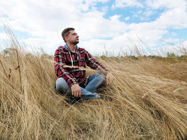 Человек сидит и отдыхает посреди осеннего поля на природе. — стоковое фото