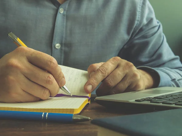 Un hombre hace cálculos en un cuaderno. Financiación interna, préstamos e impuestos. — Foto de Stock