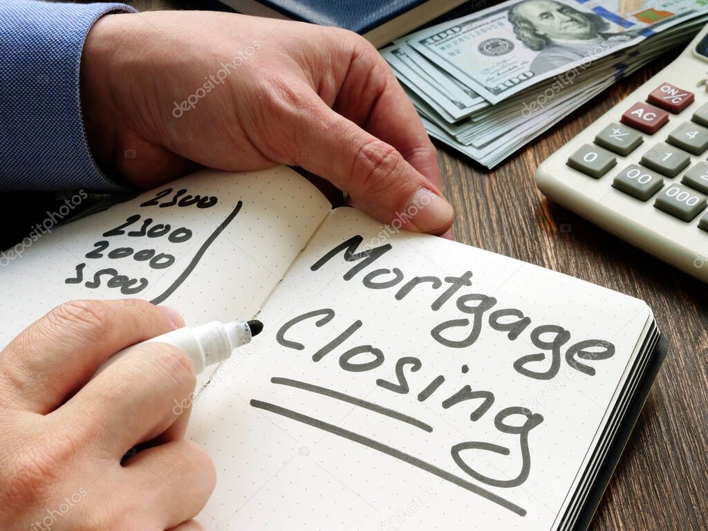 Mortgage closing. A young man makes a note in a notebook with calculations.