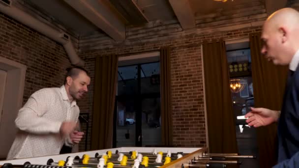 Dois homens jogam futebol de mesa à noite. Construção de equipes e recreação. — Vídeo de Stock