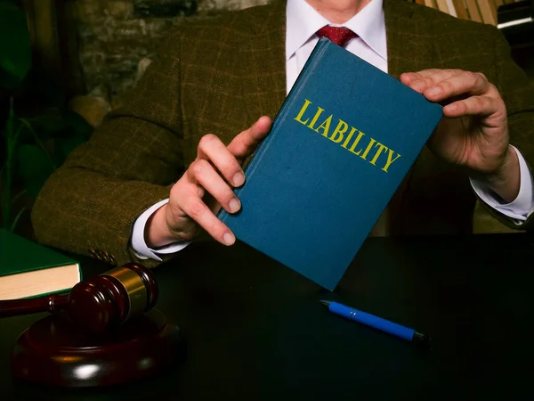 O advogado na tabela mostra uma lei de responsabilidade do livro. — Fotografia de Stock