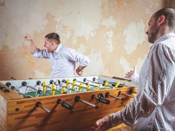 A man celebrates a victory in table football. Evening activities and relaxation. — Stock Photo, Image