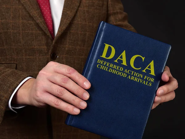 Deferred Action for Childhood Arrivals DACA concept. Man in suit shows the book. — Stock Photo, Image