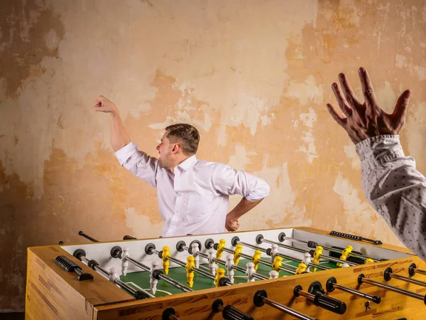 A young man celebrates a victory in table football. Evening active rest. — Stock Photo, Image