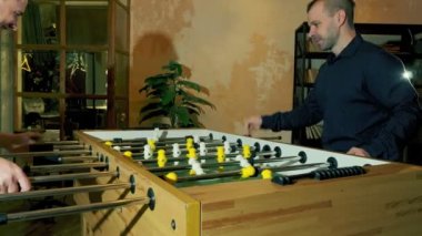 İki erkek akşamları masa futbolu oynarken eğleniyor..