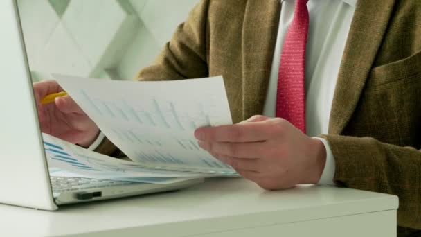 Un hombre de negocios analiza las cartas de negocios y trabaja con papeles mientras está sentado en la mesa. — Vídeos de Stock