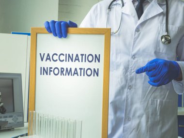 Ellerindeki beyaz tahtada aşı bilgisi işareti var..