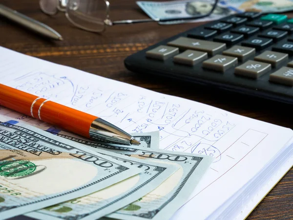 Financial calculations written by hand in a notebook, dollars and a calculator. — Stock Photo, Image
