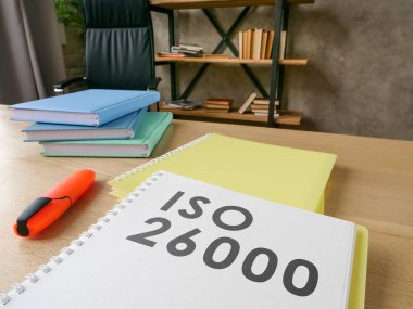Desk with guide about iso 26000 on it. clipart
