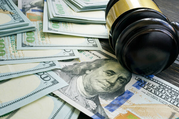 Court gavel on the money as symbol of bribes, fines and sanctions.
