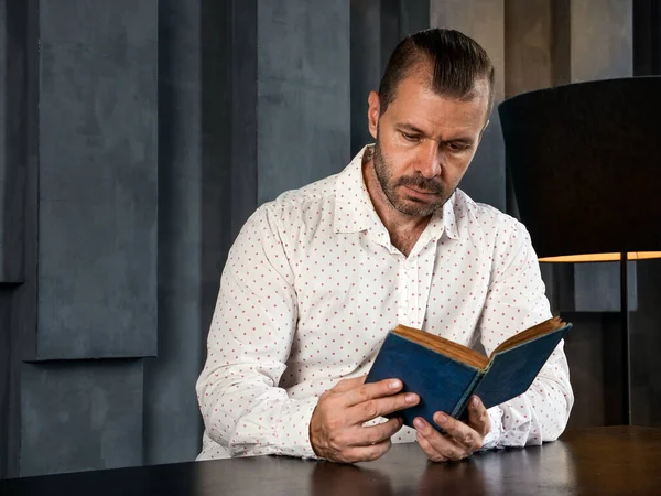 El hombre lee un libro vintage en la habitación oscura. — Foto de Stock