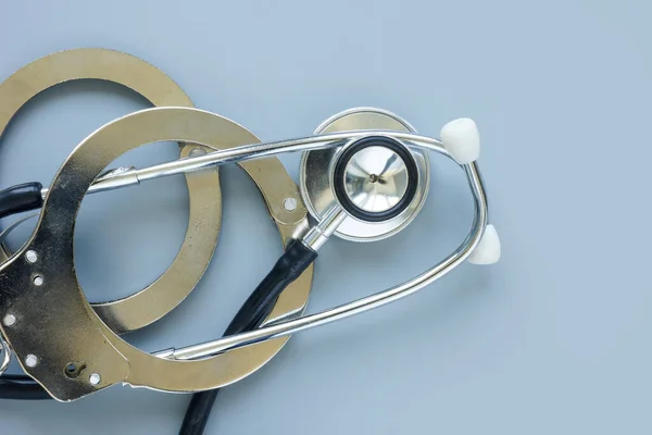 Concept de négligence ou d'erreur médicale. Menottes et stéthoscope. — Photo