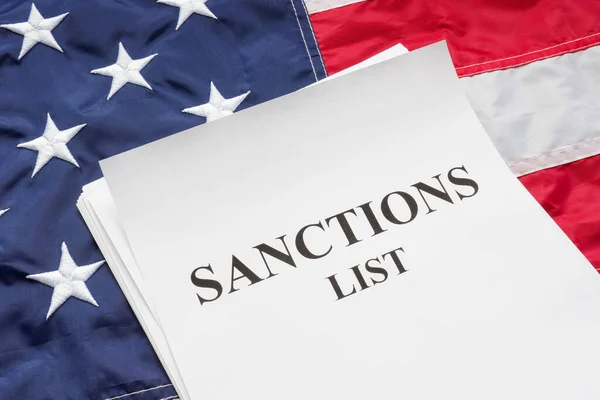 Stati Uniti bandiera e sanzioni elenco mucchio di carte su di esso. — Foto Stock