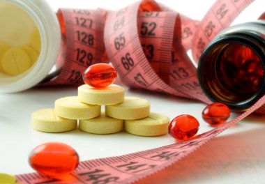 Measuring tape and bottle with pills. supplements of diet clipart