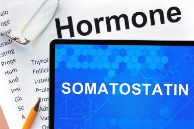Papers with hormones list and tablet  with words  Somatostatin. clipart