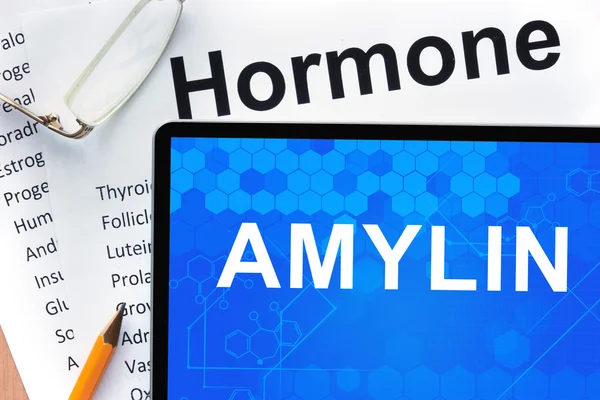 Papper med hormoner lista och tablett med ord amylin. — Stockfoto