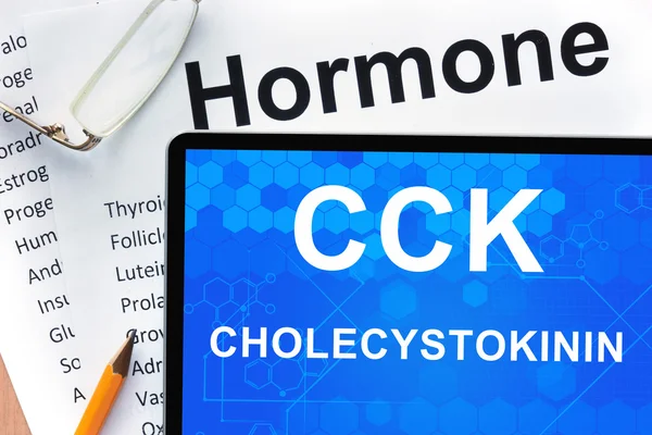 Papeles con lista de hormonas y tabletas con palabras Colecistocinina (CCK ) . —  Fotos de Stock