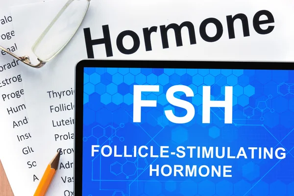 Papeles con lista de hormonas y tabletas con palabras hormona foliculoestimulante (FSH) ). — Foto de Stock