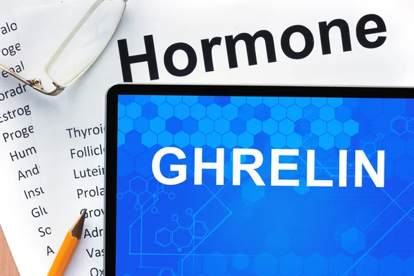 Papiere mit Hormonliste und Tablette mit den Worten Ghrelin. — Stockfoto