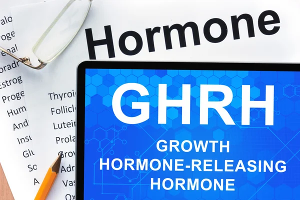 Papiery z listy hormonów i tabletki z napisem hormon uwalniający hormon wzrostu (GHRH)  . — Zdjęcie stockowe
