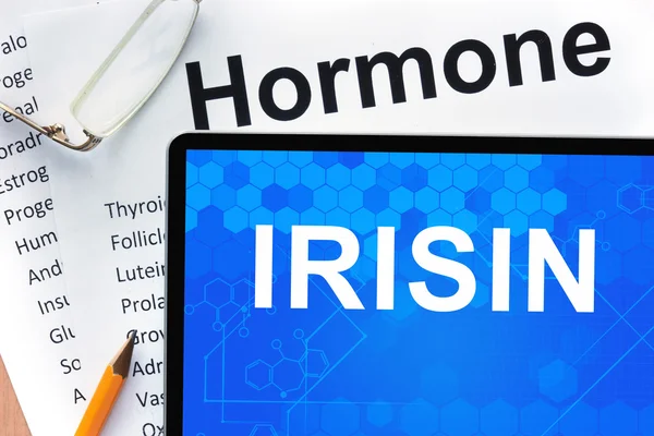 Papeles con lista de hormonas y tabletas con palabras irisina . — Foto de Stock