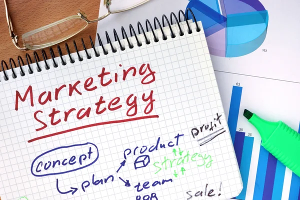 Blocco note con concetto di strategia di marketing su una tavola di legno . — Foto Stock