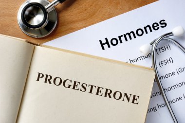 progesterone  word written on the book and hormones list. clipart