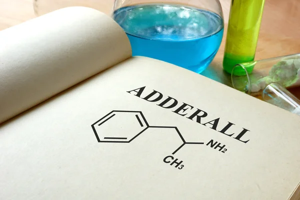 Livre avec adderall et éprouvettes sur une table . — Photo