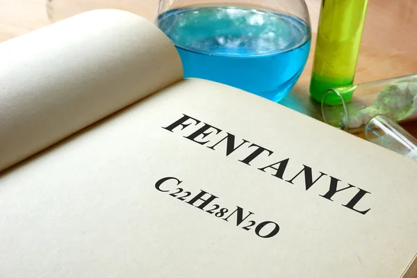 Libro con fentanil e provette su un tavolo . — Foto Stock