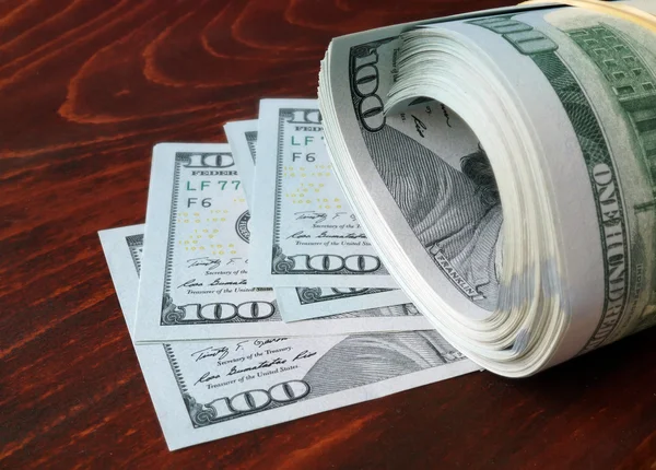 Стек 100 нас банкнот доларів на фоні дерев'яні. — стокове фото