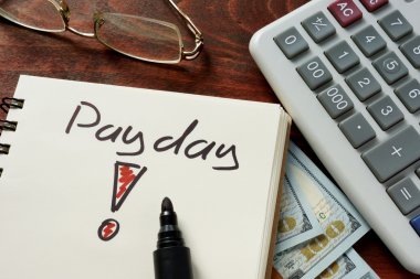Payday  written on notebook with calculator. clipart