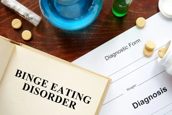 Binge-Eating-Störung auf Buch und Diagnoseformular geschrieben. — Stockfoto