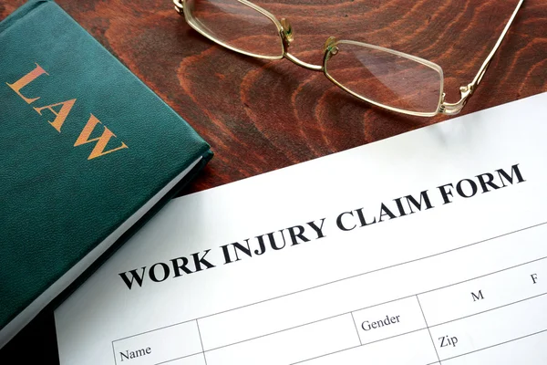 Work injury claim form on a wooden table. Stock Picture