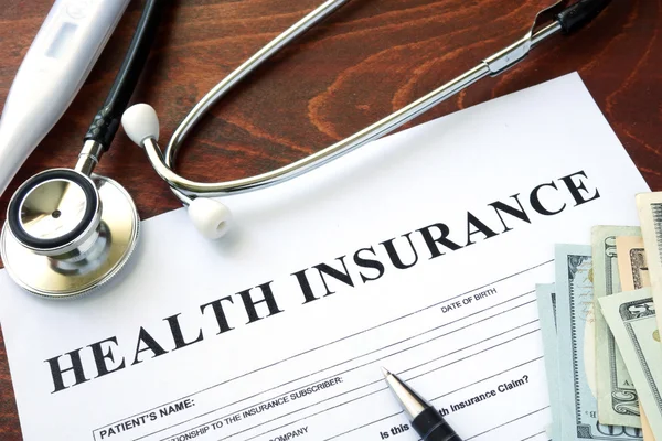 Health insurance vorm en dollars op de tafel. — Stockfoto