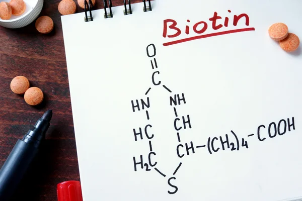 Notepad dengan biotin dan pil di atas meja . — Stok Foto