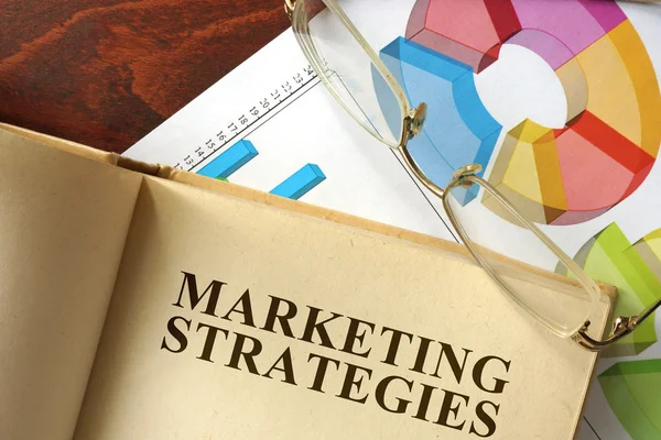 Libro con estrategias de marketing en la mesa de madera . — Foto de Stock