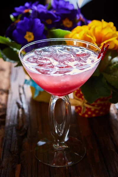 Cosmopolitan cocktail garnished with ice on wooden table — Stock Photo, Image