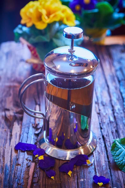 Thé aux fleurs dans un pot en verre sur une table en bois . — Photo