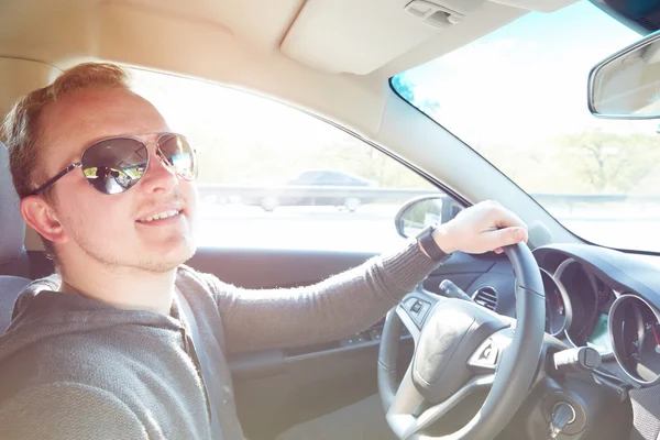 Hombre guapo conduciendo coche con gafas de sol — Foto de Stock