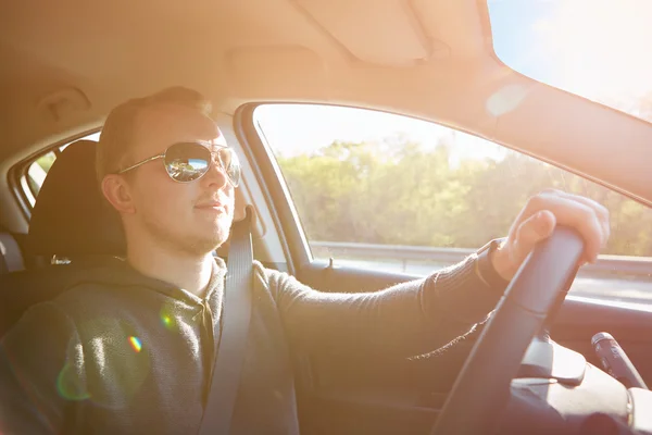 Bonito homem dirigindo carro usando óculos de sol — Fotografia de Stock