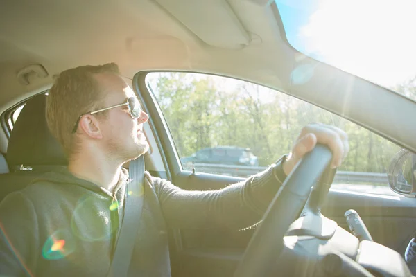 Bonito homem dirigindo carro usando óculos de sol — Fotografia de Stock