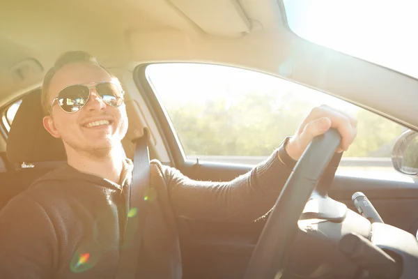 Hombre guapo conduciendo coche con gafas de sol — Foto de Stock