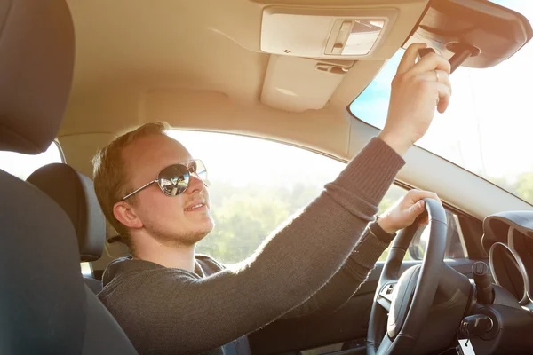 Bonito homem dirigindo carro usando óculos de sol — Fotografia de Stock