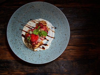 Tam buğday Belçika waffle şurubu ile tepesinde, çırpılmış krema, ceviz ve taze doğranmış çilek