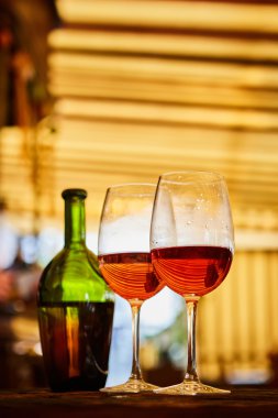 iki kadeh kırmızı şarap ve arka planda şişe dolu