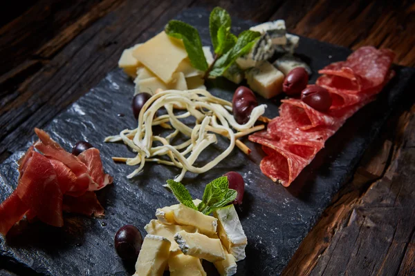 Salami and cheese platter with herbs — Stock Photo, Image