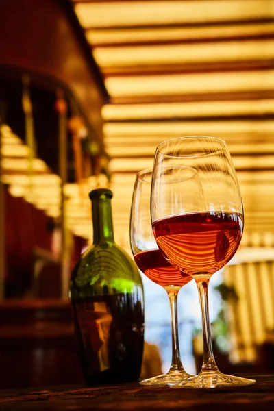 Dos vasos llenos de vino tinto y botella en el fondo —  Fotos de Stock