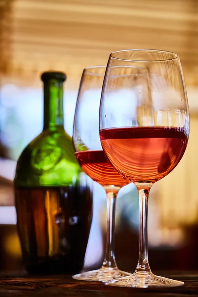 Dos vasos llenos de vino tinto y botella en el fondo — Foto de Stock