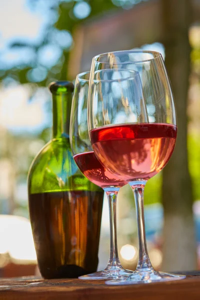 Dos vasos llenos de vino tinto y botella en el fondo — Foto de Stock